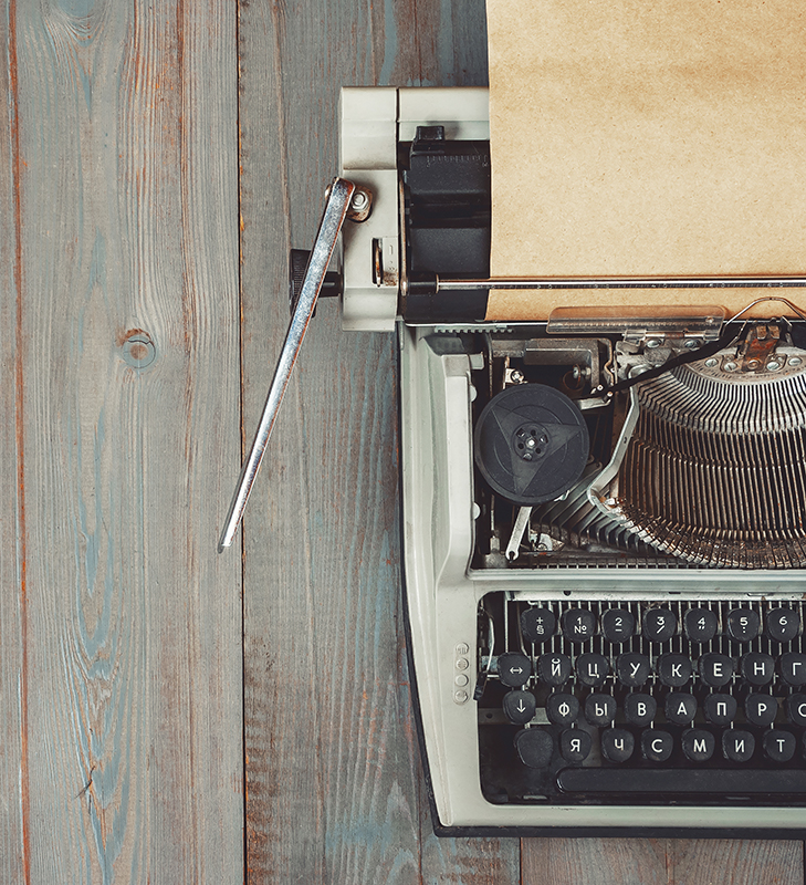 Fragment of an old typewriter with paper standing on a wooden table