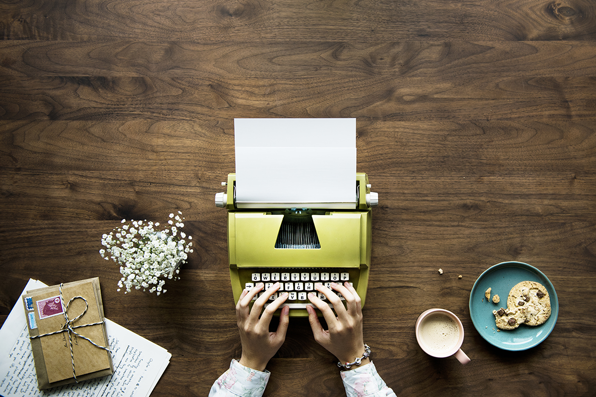 Aerial view of a woman typing on a retro typewriter blank paper